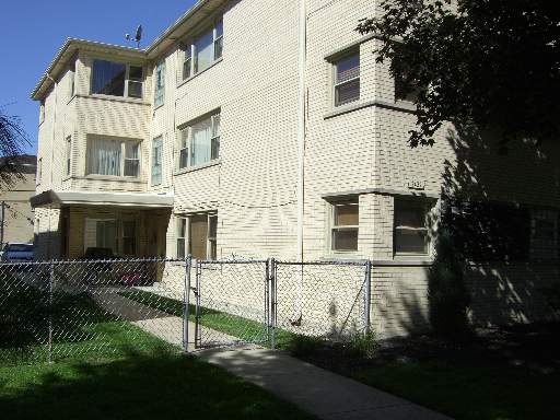 Front view of a multi-story residential building with a fence in front.