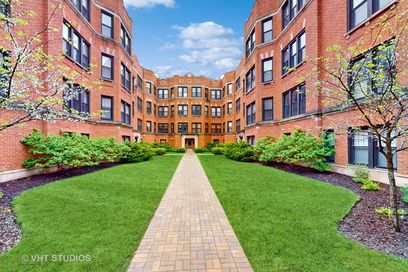 Front view of a brick apartment building with multiple floors and windows.
