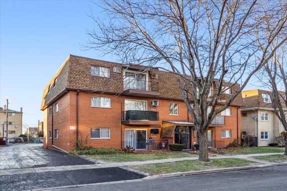Front view of a multi-story brick apartment building with balconies.
