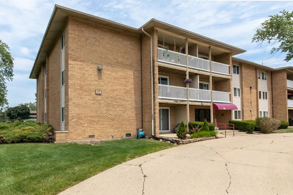 Front view of a multi-story brick apartment building with balconies.