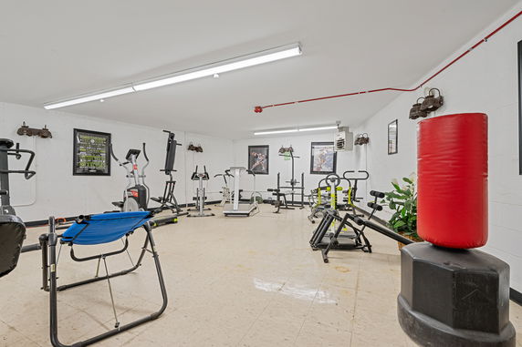 Interior view of a gym with exercise equipment including a punching bag, elliptical machines, and weight benches.