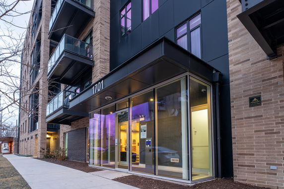 Front view of a multi-story apartment building with glass entrance and balconies.