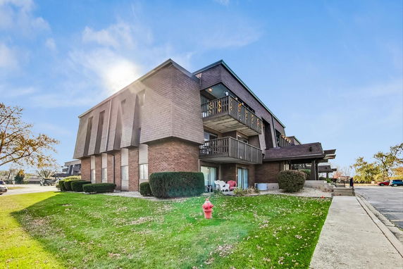 Front view of a multi-story brick and wood apartment building with balconies.