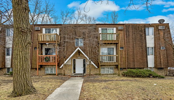 Front view of a three-story apartment building with brown siding and balconies.