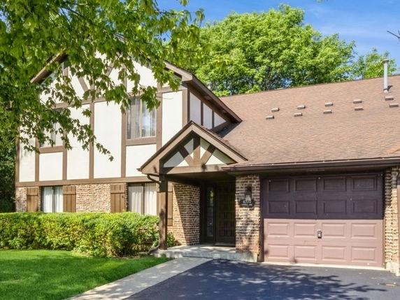 Front view of a two-story house with a garage and a brown roof.