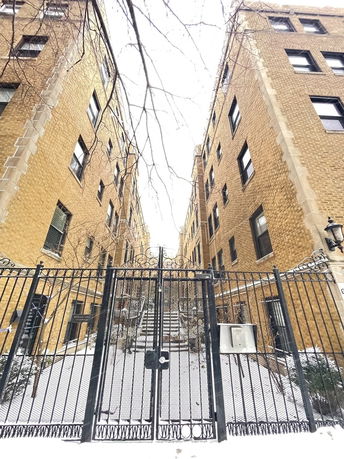 Front view of an apartment building with a gated entrance and snow-covered steps.