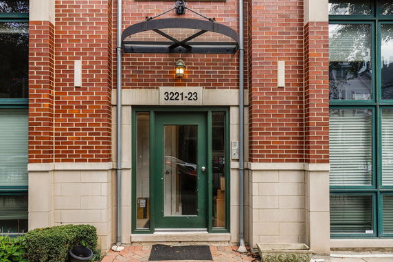 Front view of a building entrance with brick walls and a green door.