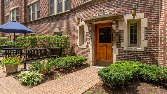 Front view of a brick building with a wooden door and decorative stonework.