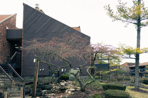 Side view of a multi-story building with dark wooden paneling and brick sections.