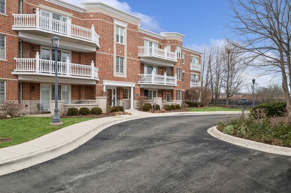 Front view of a multi-story brick building with balconies and a driveway.