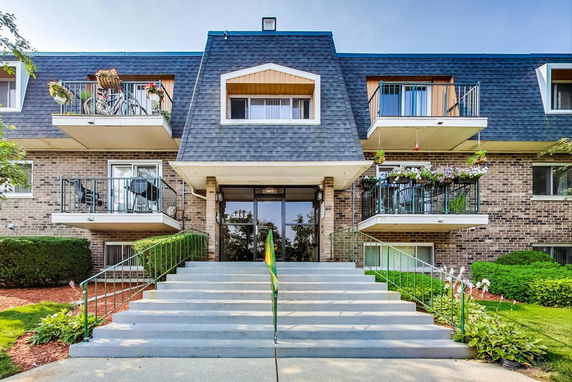 Front view of a multi-story residential building with balconies and a central entrance.