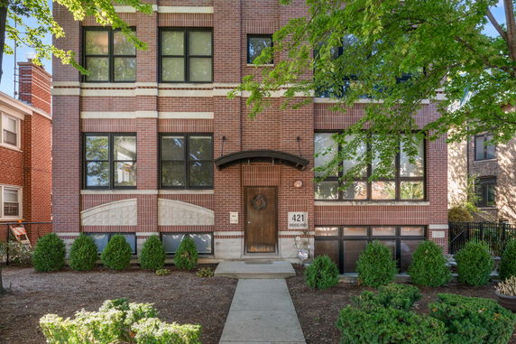 Front view of a multi-story brick building with large windows.