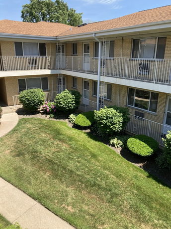 Front view of a two-story apartment building with a central courtyard and metal railings.