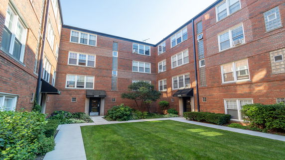 Front view of a multi-story brick apartment building with multiple entrances.