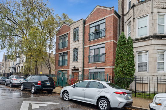 Front view of a three-story brick apartment building with balconies.