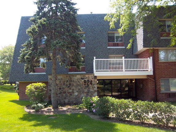 Front view of a multi-story building with a balcony and brick exterior.