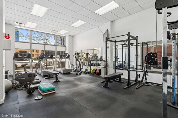 Interior view of a gym with exercise equipment, including treadmills and weights.