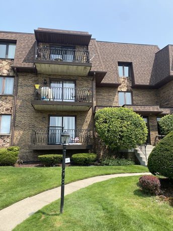 Front view of a three-story brick apartment building with balconies.