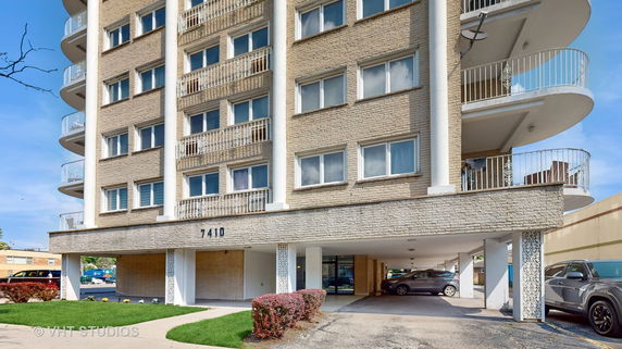 Front view of a multi-story building with balconies and a covered parking area.