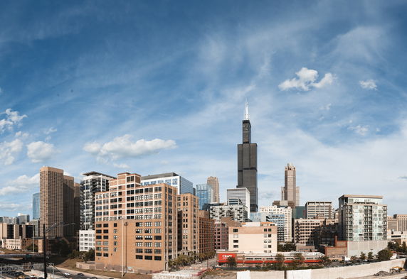 Panoramic view of city skyline with several skyscrapers and buildings under a blue sky.