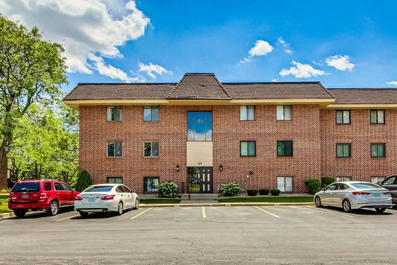 Front view of a brick apartment building with a symmetrical design and a main entrance.