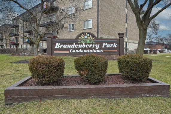 Front view of a multi-story condominium building with a sign reading 'Brandenberry Park Condominiums'.