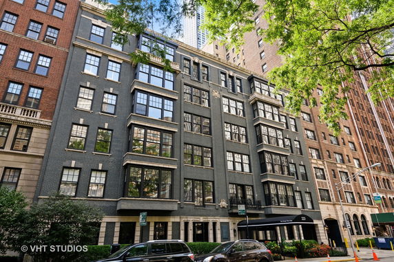 Front view of a multi-story residential building with large windows and a dark facade.