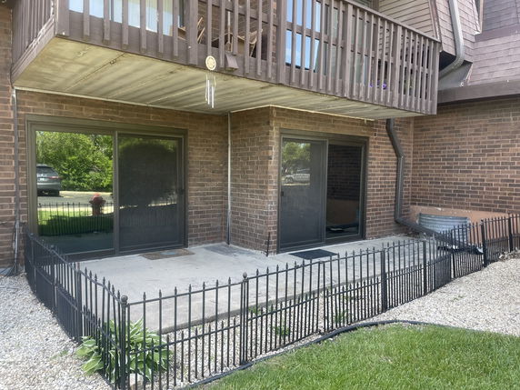 Front view of a two-story brick building with sliding glass doors and a small patio area.