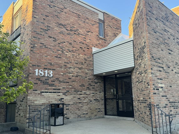 Front view of a brick building entrance with the number 1813.
