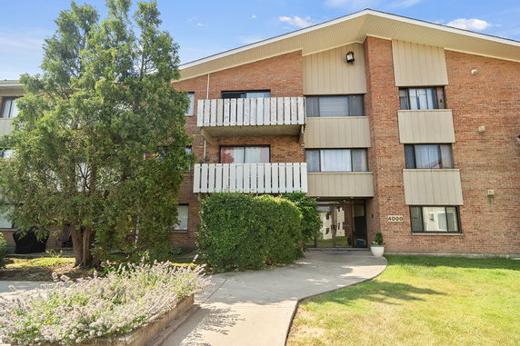 Front view of a multi-story apartment building with brick facade and balconies.