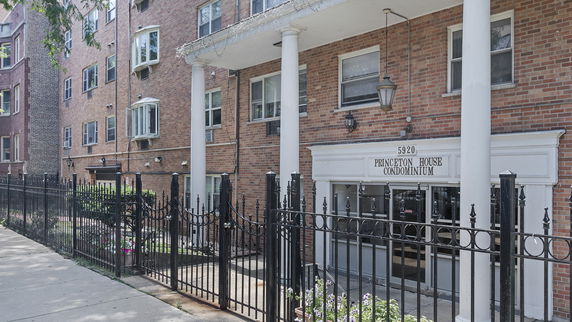 Front view of a condominium building with brick exterior and white columns.