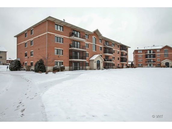 Front view of a multi-story brick residential building in a snowy setting.
