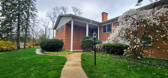 Front view of a two-story house with a brick exterior and a porch with columns.