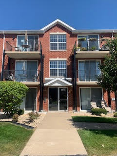 Front view of a three-story brick apartment building with balconies.