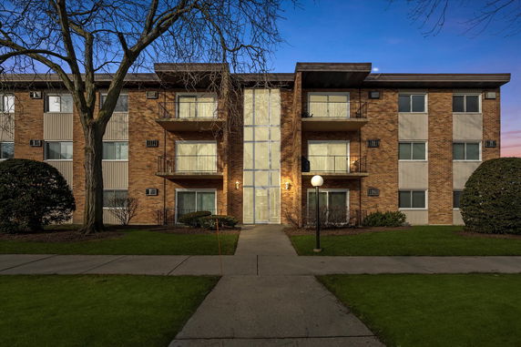 Front view of a three-story brick apartment building with balconies.