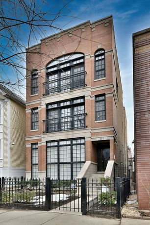 Front view of a multi-story brick building with large windows and a gated entrance.