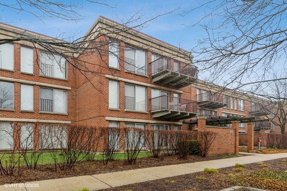 Front view of a multi-story brick apartment building with balconies.