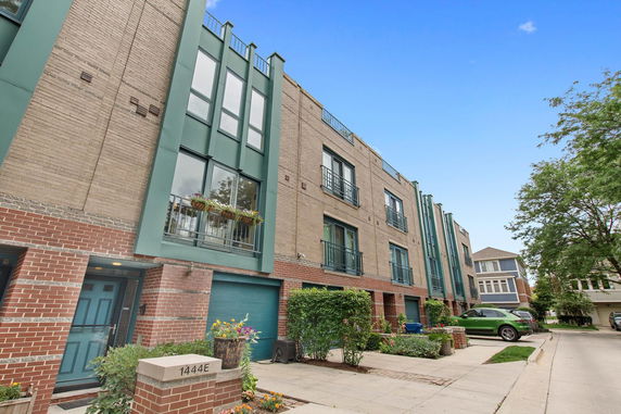Front view of a multi-story residential building with balconies and garages.