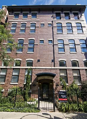 Front view of a multi-story brick building with arched windows and a central entrance.