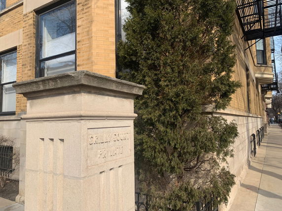 Side view of a brick building with stone detailing and metal railings.