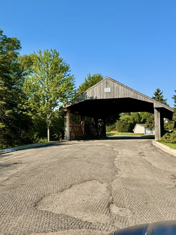 Front view of a wooden structure with a gabled roof over a road.