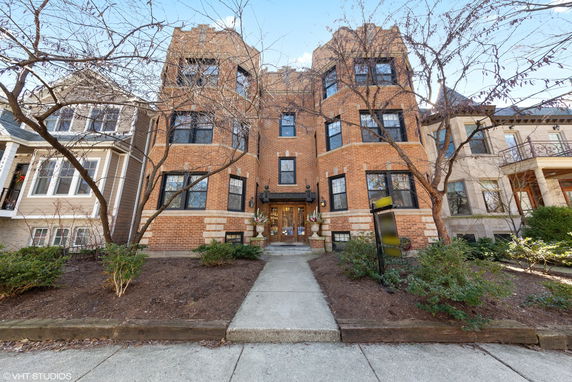 Front view of a multi-story brick building with large windows and a central entrance.