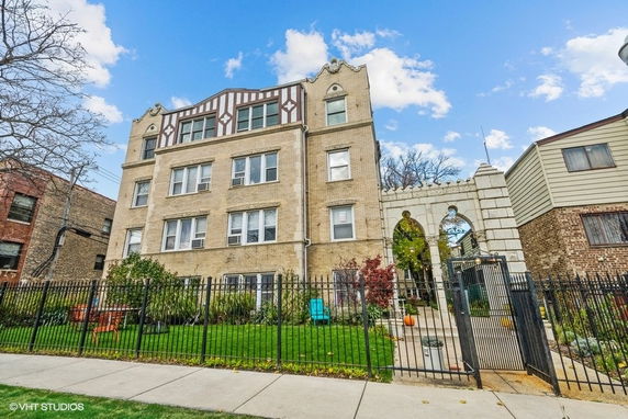 Front view of a multi-story residential building with brick exterior and decorative elements.