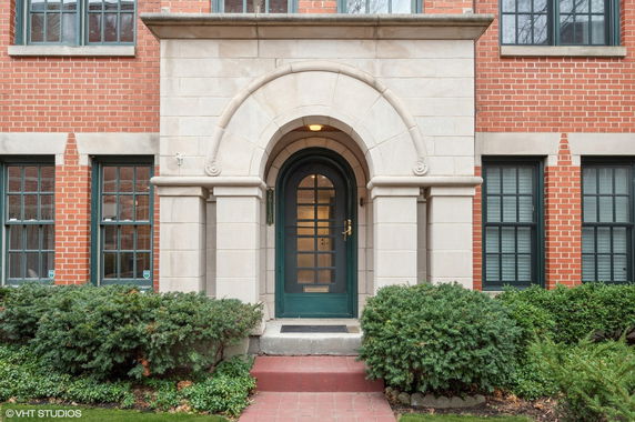 Front view of a brick building entrance with an arched doorway and windows.