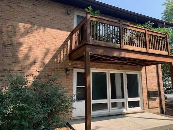 Front view of a brick house with a wooden balcony.