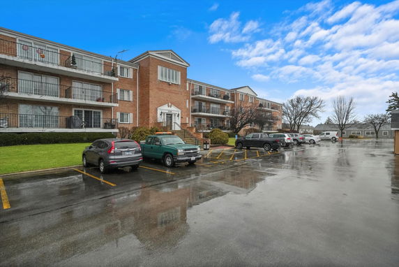 Front view of a three-story residential building with brick exterior and balconies.