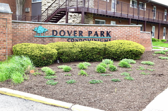Front view of a condominium building with a prominent sign and landscaping.