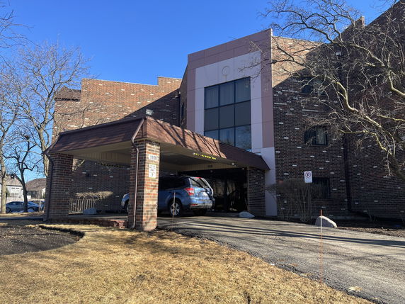 Front view of a multi-story brick building with a covered entrance.