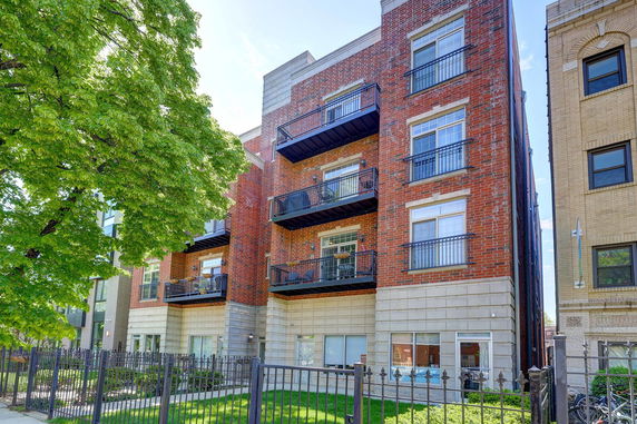 Front view of a multi-story brick apartment building with balconies.