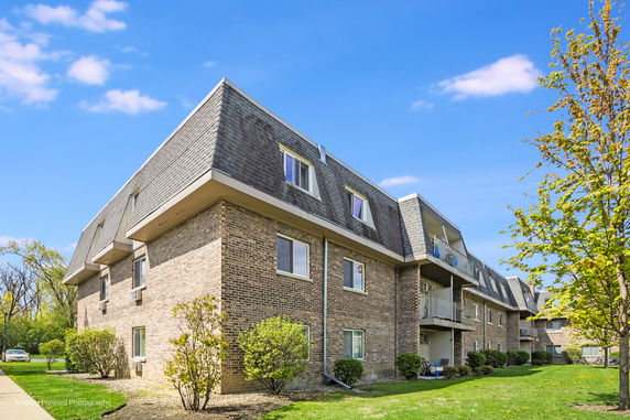 Front view of a multi-story brick apartment building with a mansard roof.